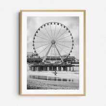 Load image into Gallery viewer, Surfer walks in front of the ferris wheel on Scheveningen Pier, framed in natural wood for a warm, classic display of this coastal scene.
