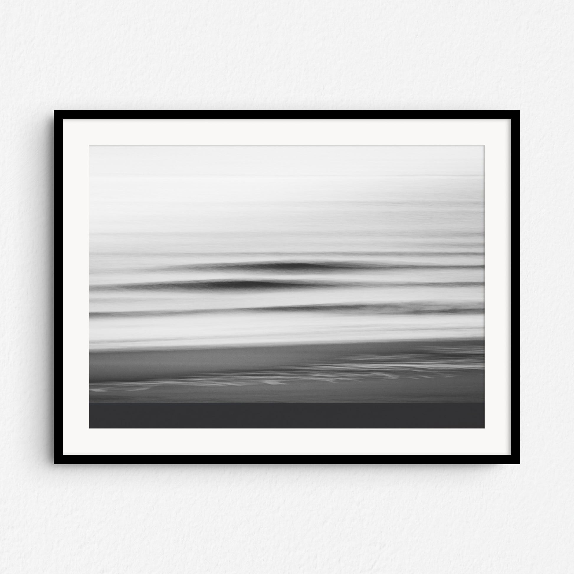 Black and white long exposure photo of breaking North Sea waves, framed in black wood. A dramatic piece for modern coastal wall decor.