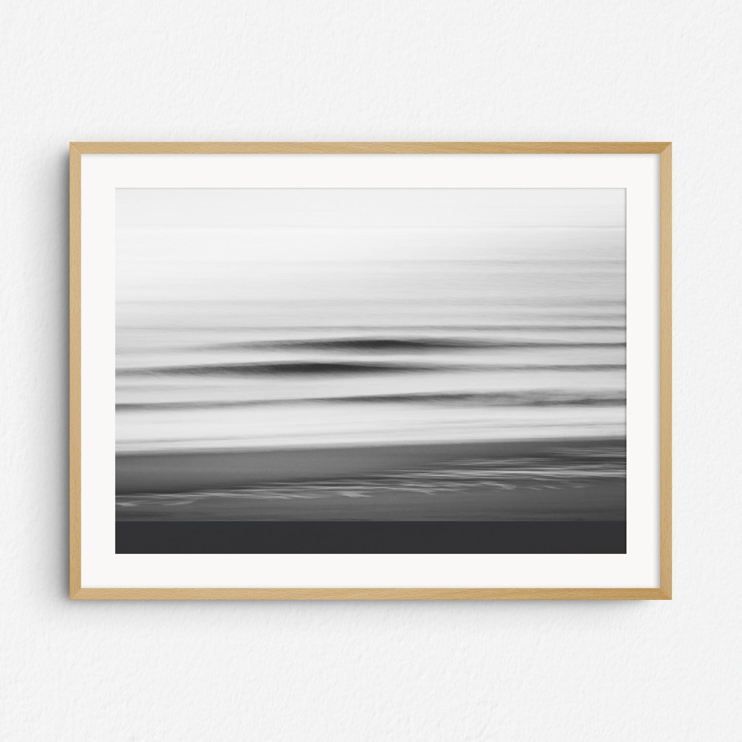 Black and white image of breaking waves captured with long exposure, framed in natural wood. Perfect for serene, nature-inspired wall art.