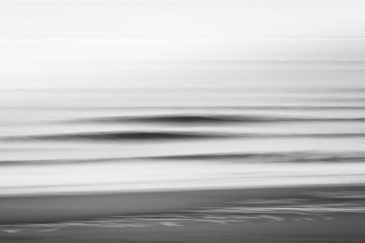 Black and white motion blur with two nice shaped waves visible on the beach of The Hague.