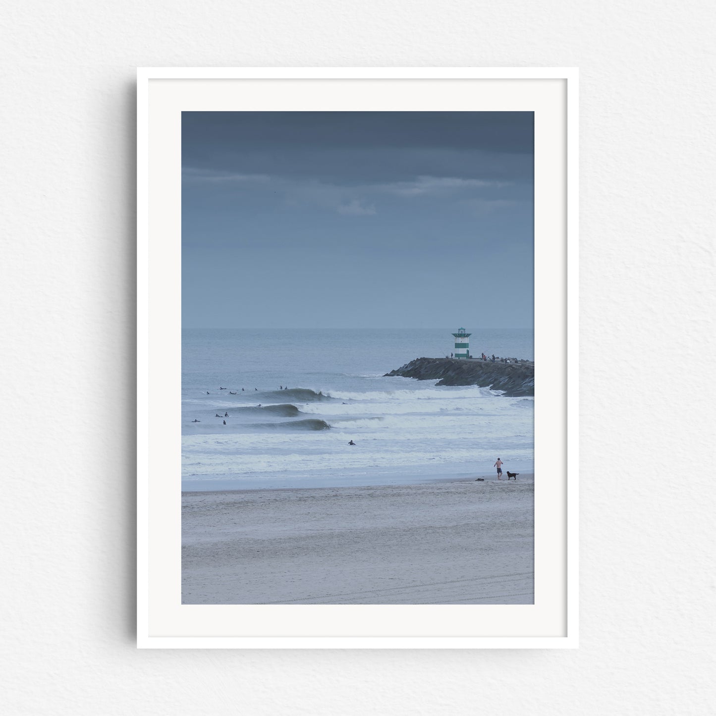 Real swell lines at the Dutch coastline next to the harbour lighthouse. Fine art print framed in white wood.