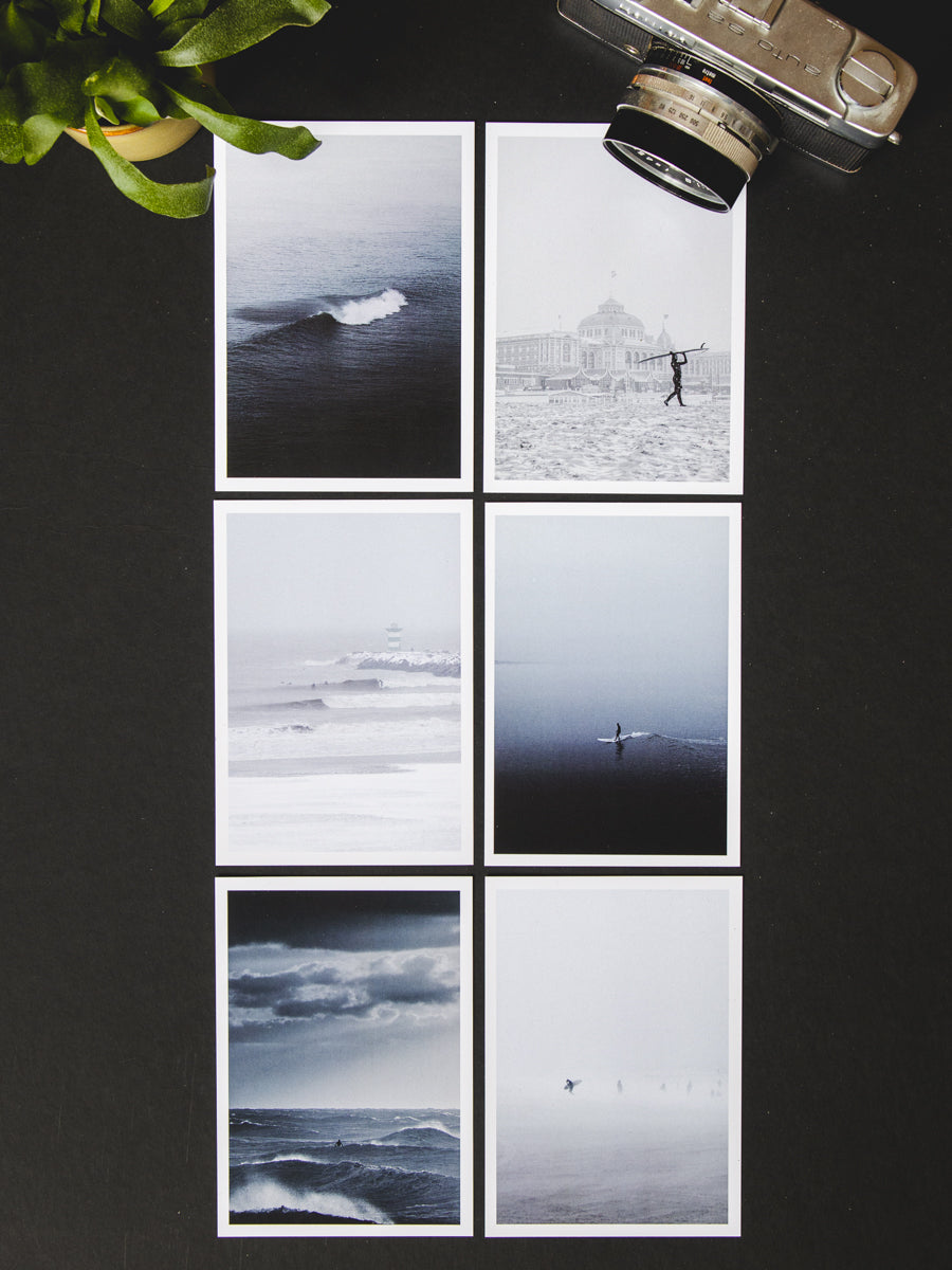 Six winter postcards photographed as a flatlay on a black surface. Surf photography captured by Jop Hermans